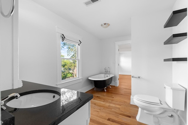 bathroom with hardwood / wood-style flooring, a bathtub, vanity, and toilet