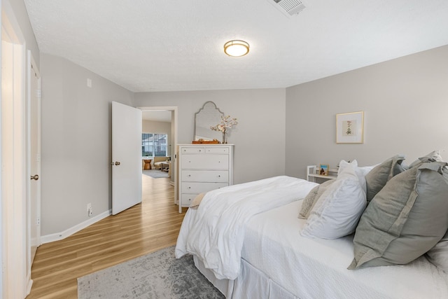 bedroom with a textured ceiling and light hardwood / wood-style flooring