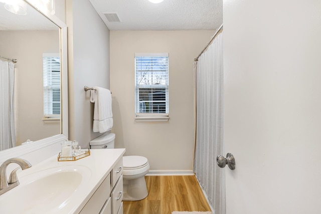 bathroom with toilet, a textured ceiling, hardwood / wood-style floors, and vanity