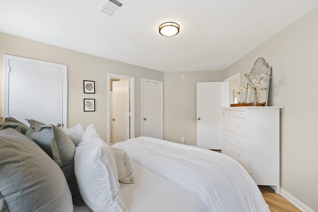 bedroom with light wood-type flooring and a textured ceiling