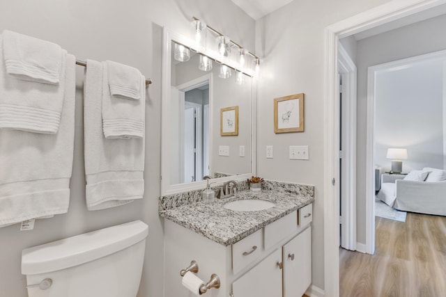 bathroom with toilet, hardwood / wood-style flooring, and vanity