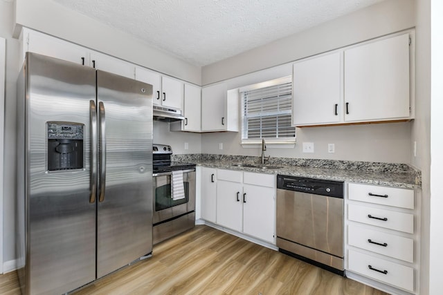 kitchen featuring light stone countertops, a textured ceiling, white cabinets, appliances with stainless steel finishes, and sink