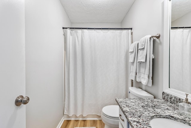 bathroom with toilet, vanity, hardwood / wood-style flooring, a textured ceiling, and a shower with shower curtain