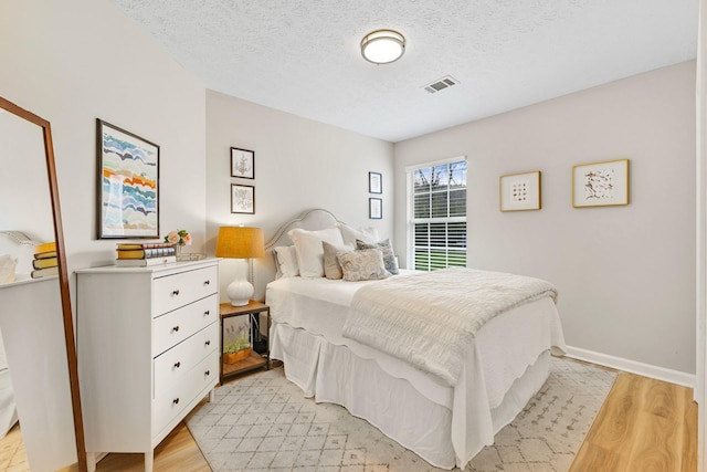 bedroom featuring light hardwood / wood-style floors and a textured ceiling