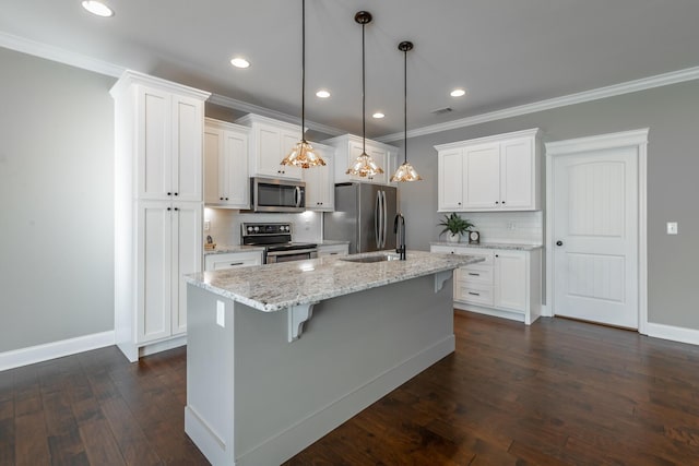 kitchen with white cabinets, hanging light fixtures, appliances with stainless steel finishes, and a center island with sink