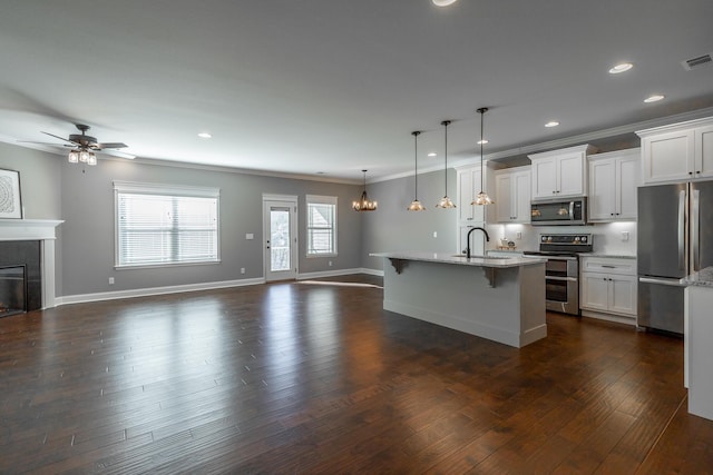 kitchen featuring pendant lighting, appliances with stainless steel finishes, sink, a breakfast bar, and a tile fireplace