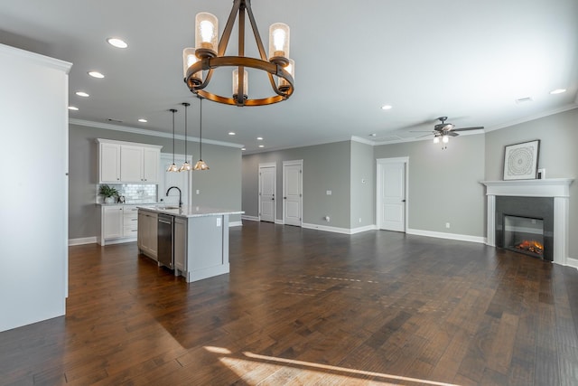 kitchen with white cabinets, decorative light fixtures, tasteful backsplash, sink, and a kitchen island with sink