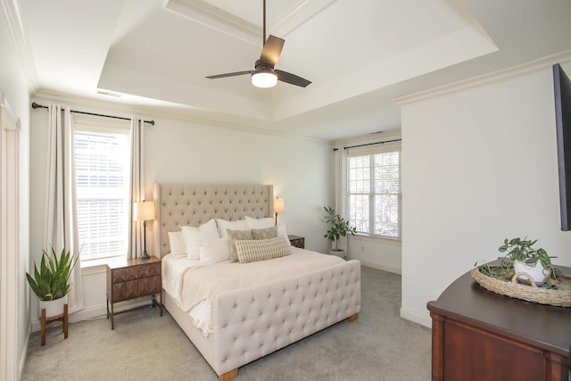 bedroom featuring light carpet, ceiling fan, ornamental molding, and a tray ceiling