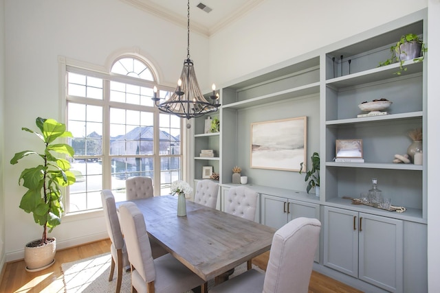 dining room featuring wood-type flooring, built in features, ornamental molding, and a notable chandelier