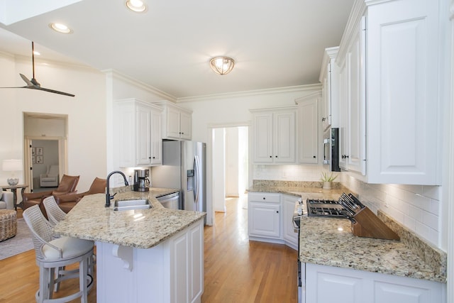 kitchen featuring white cabinetry, kitchen peninsula, stainless steel appliances, tasteful backsplash, and light stone countertops