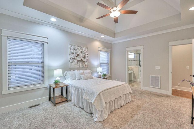 bedroom featuring ceiling fan, ensuite bathroom, a raised ceiling, and carpet flooring