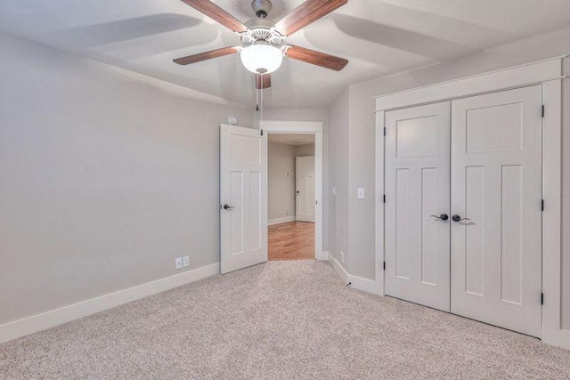 unfurnished bedroom featuring ceiling fan, a closet, and light carpet