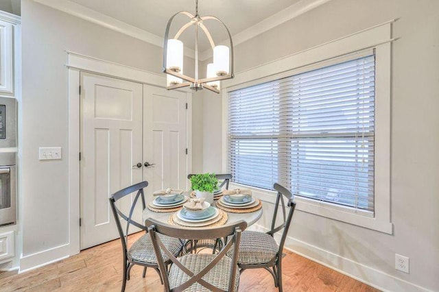 dining room with crown molding, a healthy amount of sunlight, a notable chandelier, and light wood-type flooring