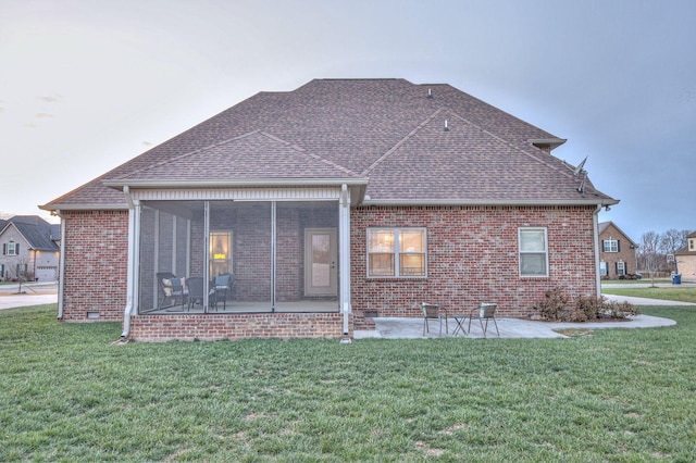 rear view of house with a sunroom, a lawn, and a patio