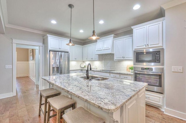 kitchen with a kitchen island with sink, appliances with stainless steel finishes, sink, and white cabinetry