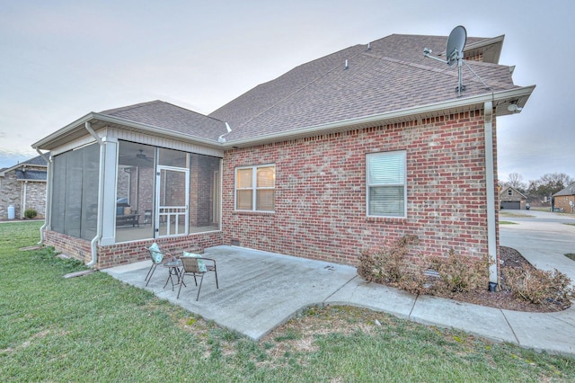 back of property featuring a patio area, a sunroom, and a lawn