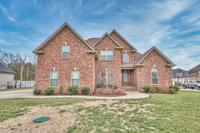 traditional-style house with a front yard, brick siding, and fence