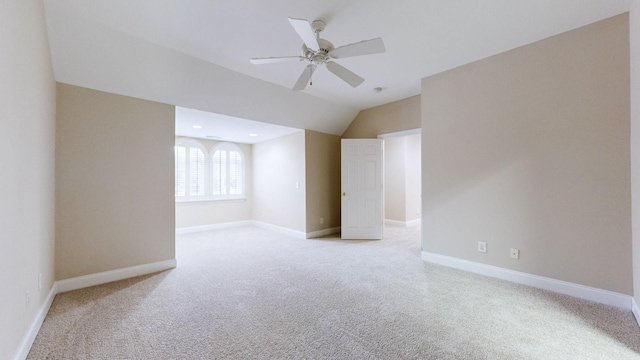 spare room with vaulted ceiling, light colored carpet, and ceiling fan