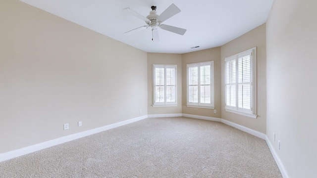 carpeted empty room with ceiling fan and plenty of natural light