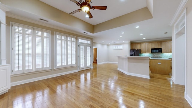 kitchen featuring decorative backsplash, black appliances, a center island, and light wood-type flooring