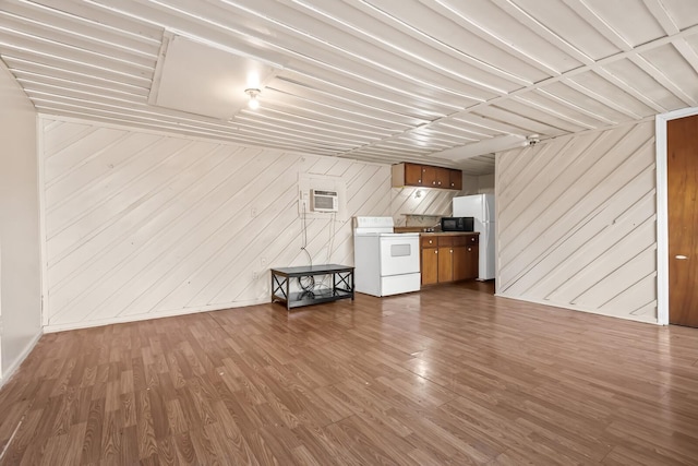 unfurnished living room featuring wood-type flooring, wood walls, and a wall mounted AC