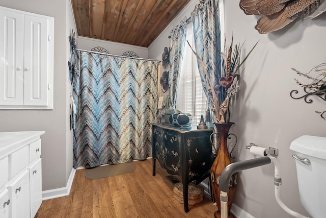 bathroom featuring toilet, hardwood / wood-style floors, wooden ceiling, crown molding, and vanity