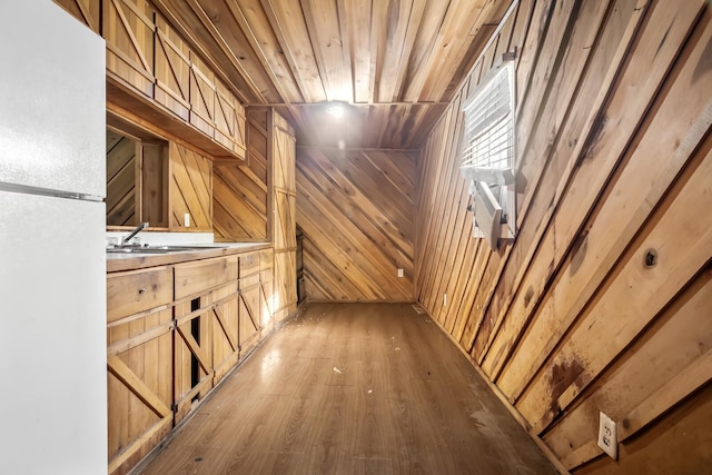 interior space featuring wood-type flooring, white fridge, wooden walls, sink, and wooden ceiling