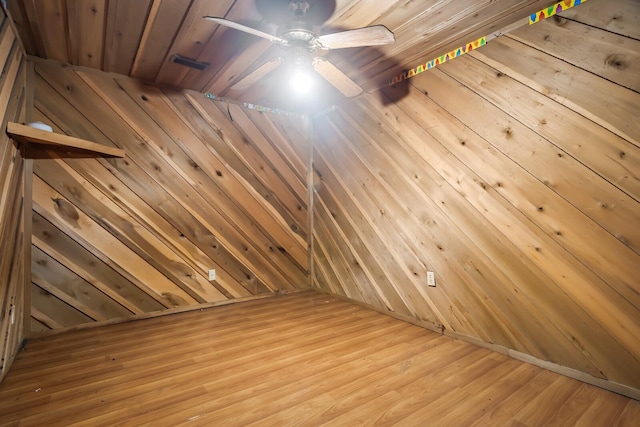 interior space featuring ceiling fan, light wood-type flooring, and wood walls