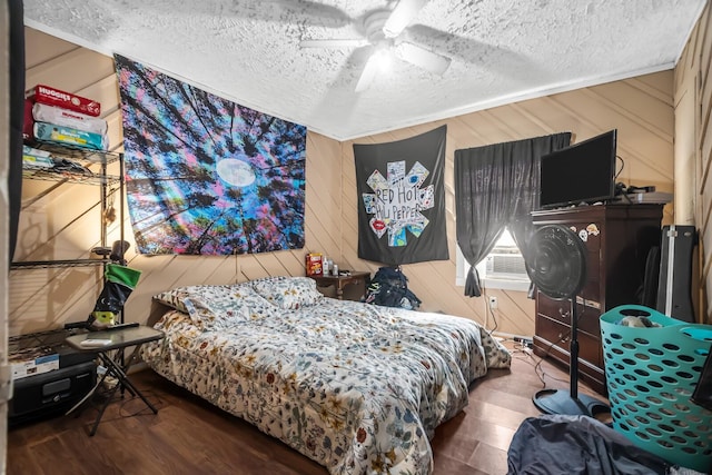 bedroom with ceiling fan, wood-type flooring, wood walls, and a textured ceiling