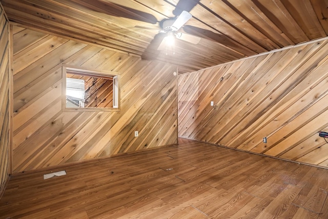 bonus room with wood walls, ceiling fan, and wood-type flooring