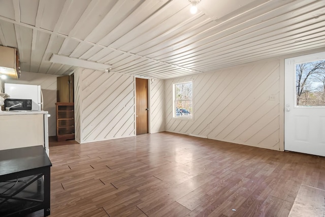 unfurnished living room featuring wood-type flooring and wooden walls