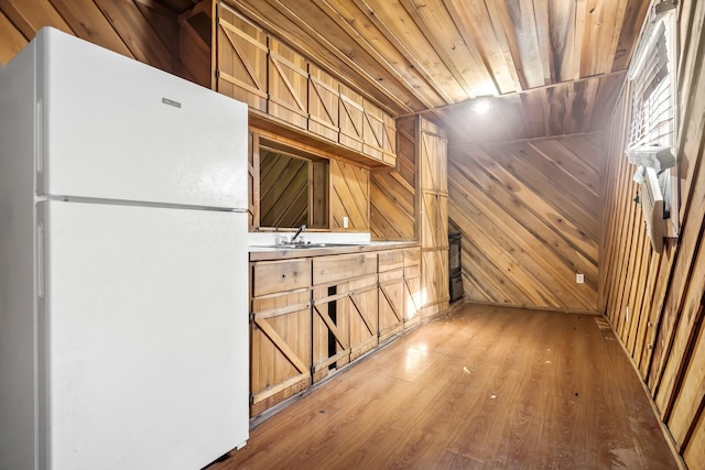 kitchen featuring white fridge, wood-type flooring, sink, wooden walls, and wood ceiling