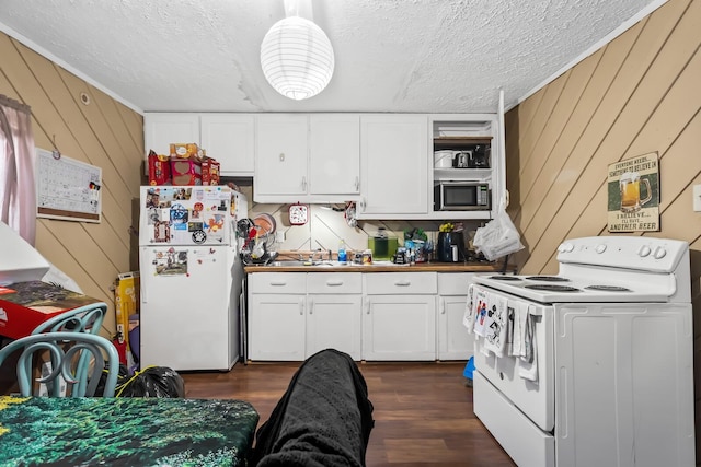 kitchen with white appliances, a textured ceiling, dark wood-type flooring, white cabinetry, and wood walls