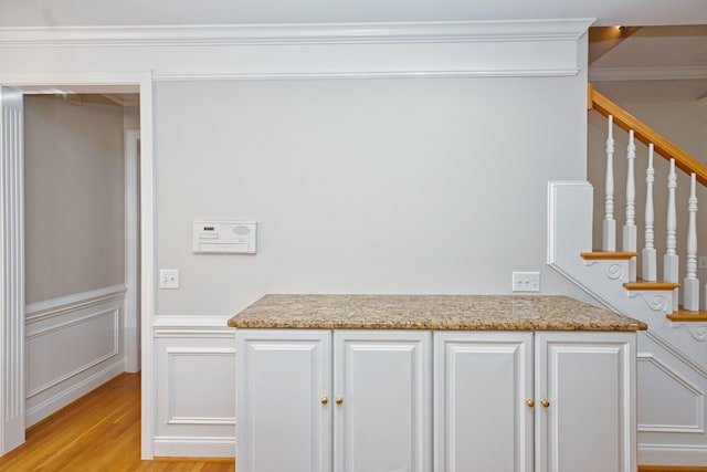 kitchen featuring crown molding, light hardwood / wood-style floors, white cabinets, and light stone counters