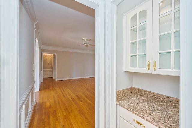 corridor with ornamental molding and light hardwood / wood-style floors