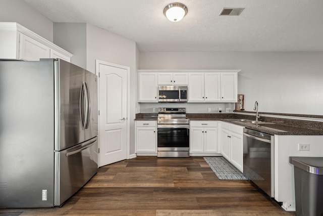 kitchen with white cabinetry, stainless steel appliances, dark hardwood / wood-style flooring, a textured ceiling, and sink