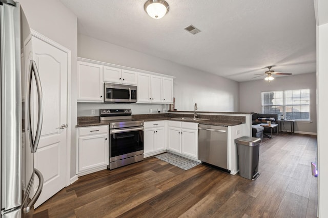 kitchen with stainless steel appliances, dark hardwood / wood-style flooring, white cabinetry, and sink