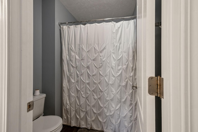 bathroom with toilet, a shower with curtain, and a textured ceiling