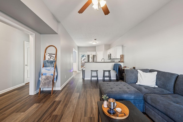 living room with a textured ceiling, ceiling fan, dark hardwood / wood-style floors, and sink