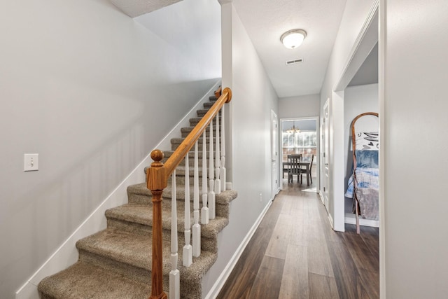 staircase with a textured ceiling and hardwood / wood-style flooring