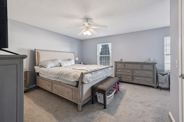 bedroom with ceiling fan, light colored carpet, and multiple windows