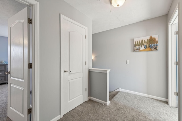 corridor with carpet and a textured ceiling