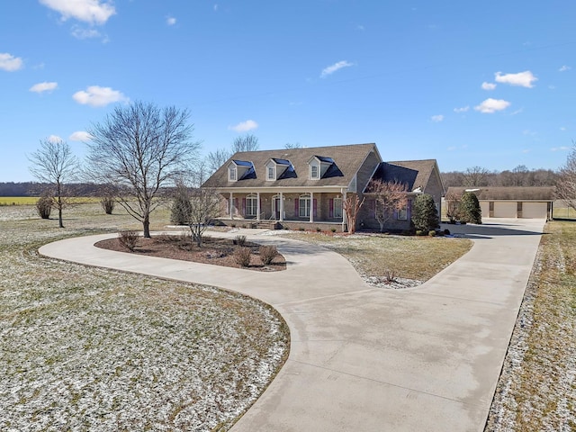 cape cod home with covered porch, a front yard, and a garage