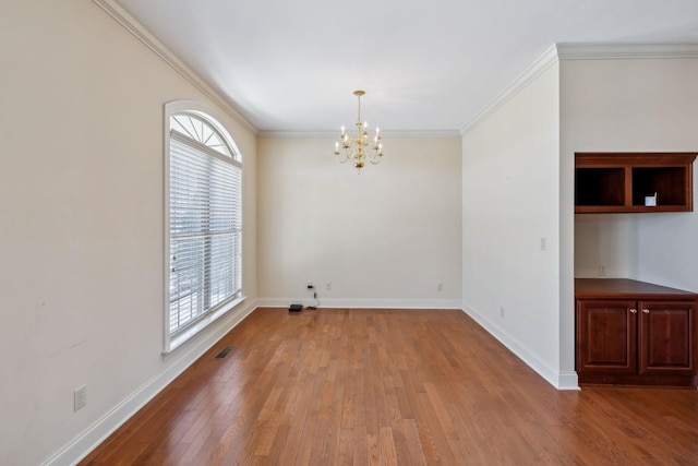 empty room featuring an inviting chandelier, a wealth of natural light, crown molding, and wood-type flooring