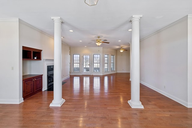 unfurnished living room with ceiling fan, ornamental molding, and decorative columns