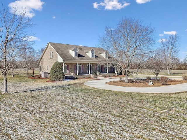 cape cod home with a front lawn, central air condition unit, and covered porch