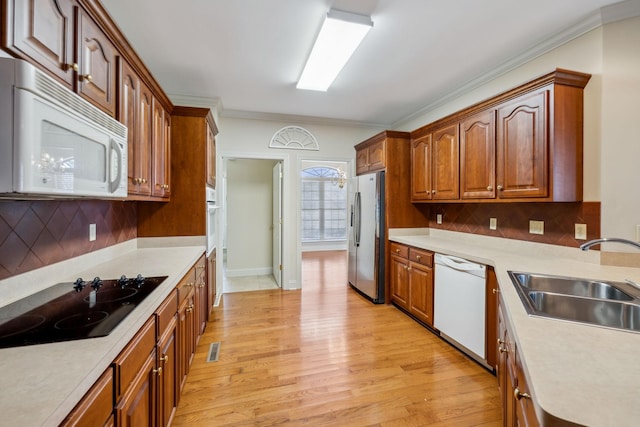 kitchen with sink, white appliances, backsplash, and crown molding