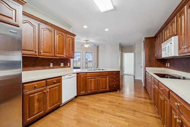 kitchen featuring light hardwood / wood-style floors, kitchen peninsula, backsplash, white appliances, and sink