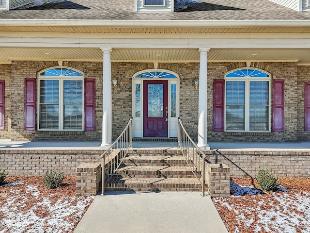 snow covered property entrance with a porch