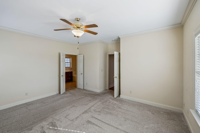 carpeted empty room with ceiling fan, crown molding, and plenty of natural light